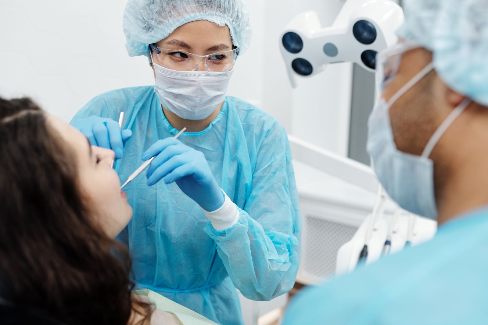 Dentist in protective gear examining a patient